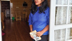 Une personne tenant un livre dans une pièce dont le sol est en bois et qui est dotée d’un plafond au design moderne.