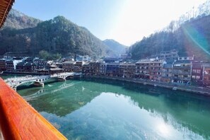A traditional town with buildings along a river, a bridge, and mountains in the background. - Fuyuan Riverview Homestay (Fenghuang County)