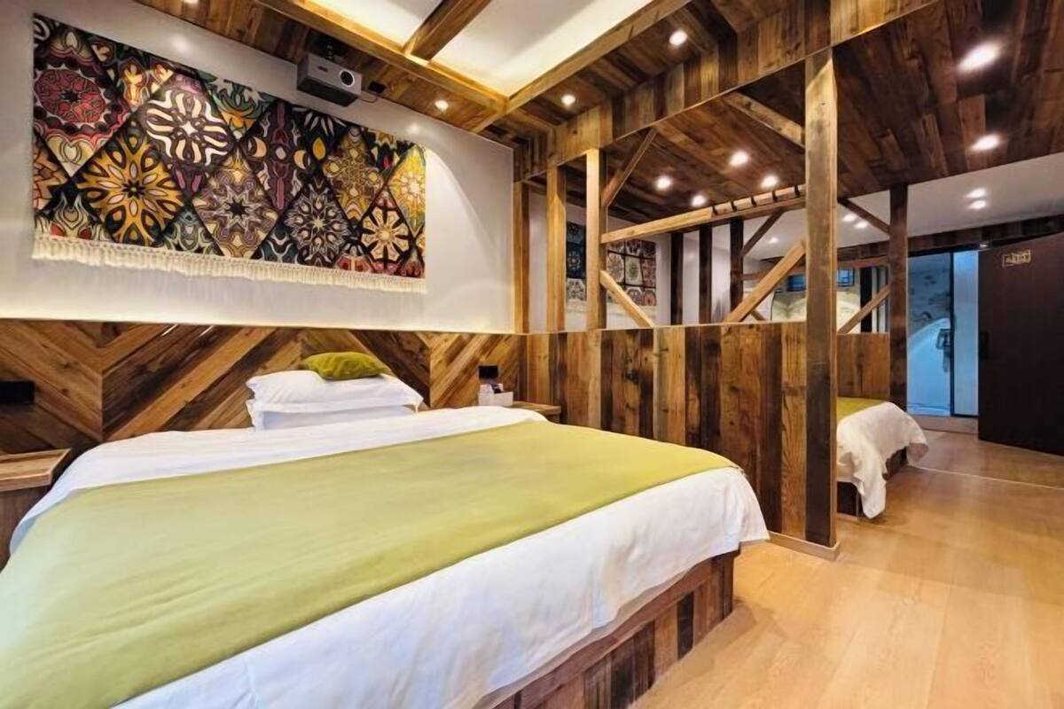 A hotel room with a bed, wooden walls, a large abstract painting, and a staircase.