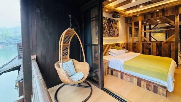 A room with a bed, a hanging chair, and a view of a body of water. - Fuyuan Riverview Homestay (Fenghuang County)