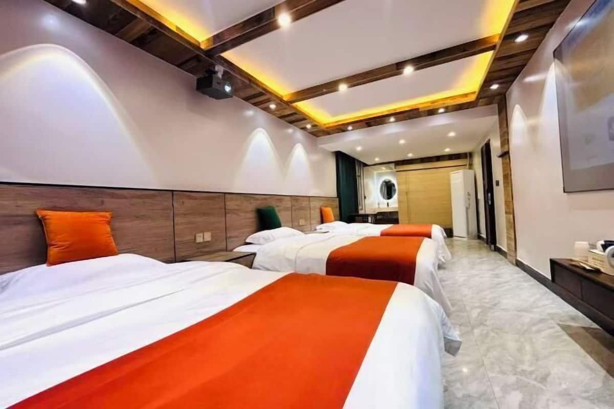 A hotel room with three beds, wooden headboards, a marble floor, and recessed lighting.
