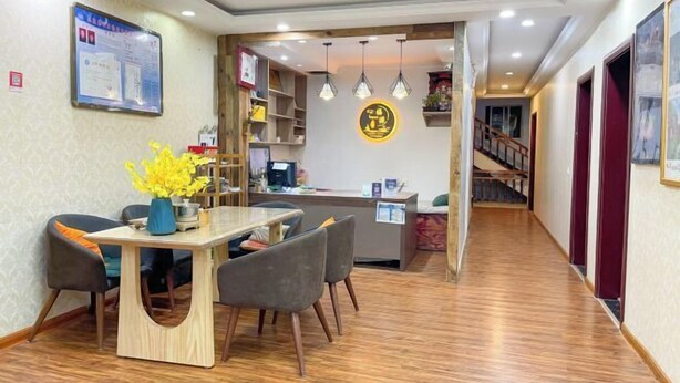 A hotel lobby with a reception desk, a dining area with a table and chairs, and a staircase leading to another floor. - Fuyuan Riverview Homestay (Fenghuang County)