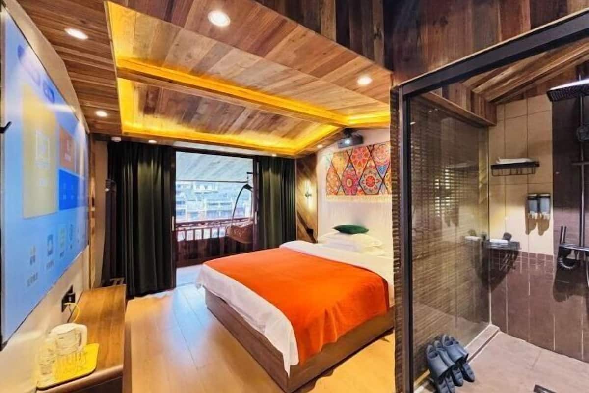 A hotel room with a bed, a shower area, and a view of the city.