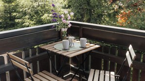 A wooden deck with a table and chairs, a vase with flowers, and a pitcher.