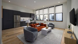Una sala de estar moderna con un sofá gris, una mesa de centro y un televisor montado en la pared.