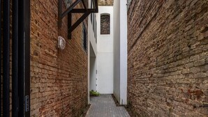 Un estrecho callejón de ladrillo con una pared blanca y una pequeña ventana.