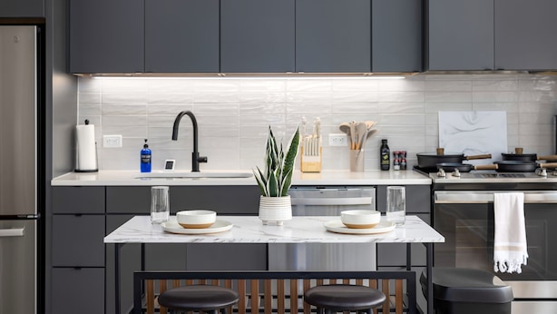 Una cocina moderna con armarios oscuros, una encimera blanca y una isla central con asientos.