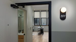 Un interior moderno con piso de madera, un área de comedor con mesa y sillas, y una lámpara de pared con el número 201.
