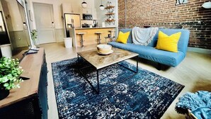 Una sala de estar moderna con un sofá azul, una mesa de centro de madera y una alfombra estampada.