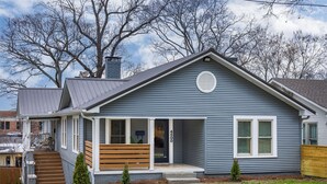 Une maison de plain-pied avec un porche à l’avant, une cheminée et un petit jardin devant.