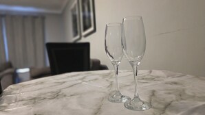 Two clear glasses on a marble table in a room with a blurred background.