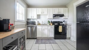 Una cocina moderna con gabinetes blancos, electrodomésticos de acero inoxidable y un refrigerador negro.