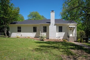A single-story house with a chimney, a front porch, and a well-maintained lawn.