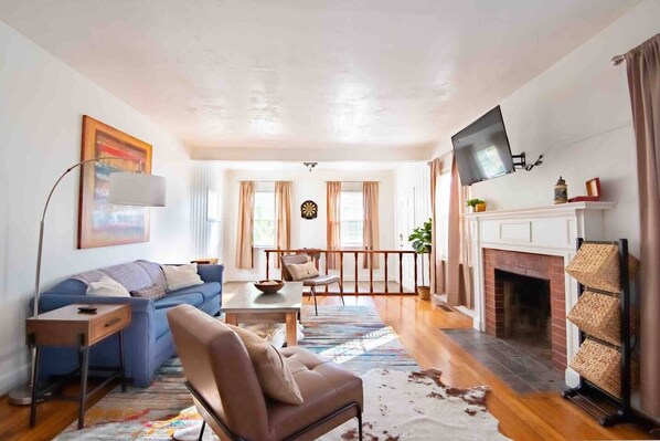 A living room with a sofa, armchair, coffee table, and fireplace.