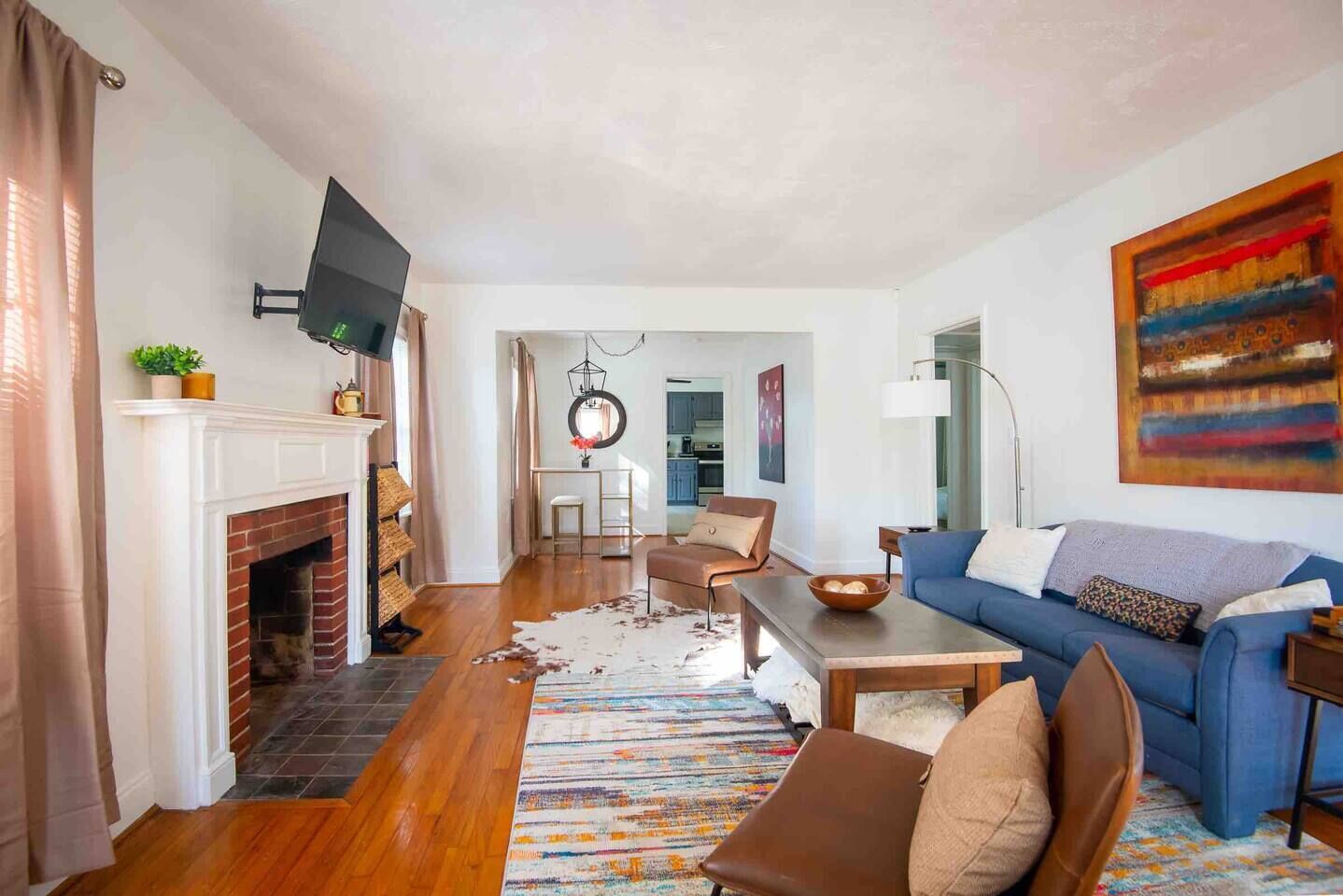 A living room with a fireplace, a blue sofa, a coffee table, and a television mounted on the wall.