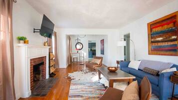 A living room with a fireplace, a blue sofa, a coffee table, and a television mounted on the wall.