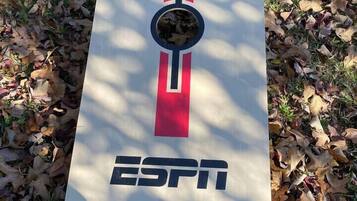 Une affiche ornée du logo d’ESPN, placée dans un espace verdoyant recouvert de feuilles mortes.