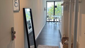 A modern hallway with a dark wooden floor, a framed picture on the wall, a coat rack, and a view of a dining area with a table and chairs. - Chic apartment in a central location with a large balcony and views over the city (Attendorn)