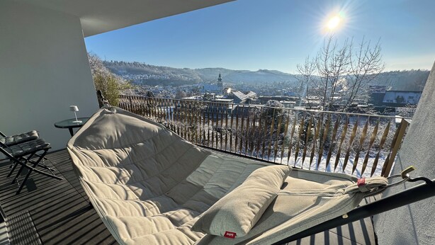 A balcony with a hammock, a small table, and a chair. - Chic apartment in a central location with a large balcony and views over the city (Attendorn)
