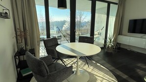 A modern living room with a round table, two chairs, a TV, and large windows with a view of a snowy landscape. - Chic apartment in a central location with a large balcony and views over the city (Attendorn)