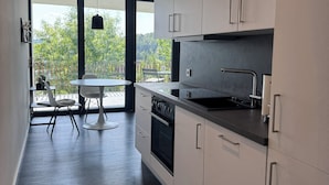 A modern kitchen with white cabinets, a black countertop, and a view of the outdoors through large windows. - Chic apartment in a central location with a large balcony and views over the city (Attendorn)