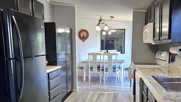 A modern kitchen with black appliances, a wooden floor, and a dining area with a table and chairs. - Affordable Pollyanna Ridge, By Norris Lake & Dam St Pk & ATV trails. 3BR 2Bath (Rocky Top)