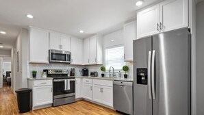 Una cocina moderna con armarios blancos, electrodomésticos de acero inoxidable y suelo de madera.