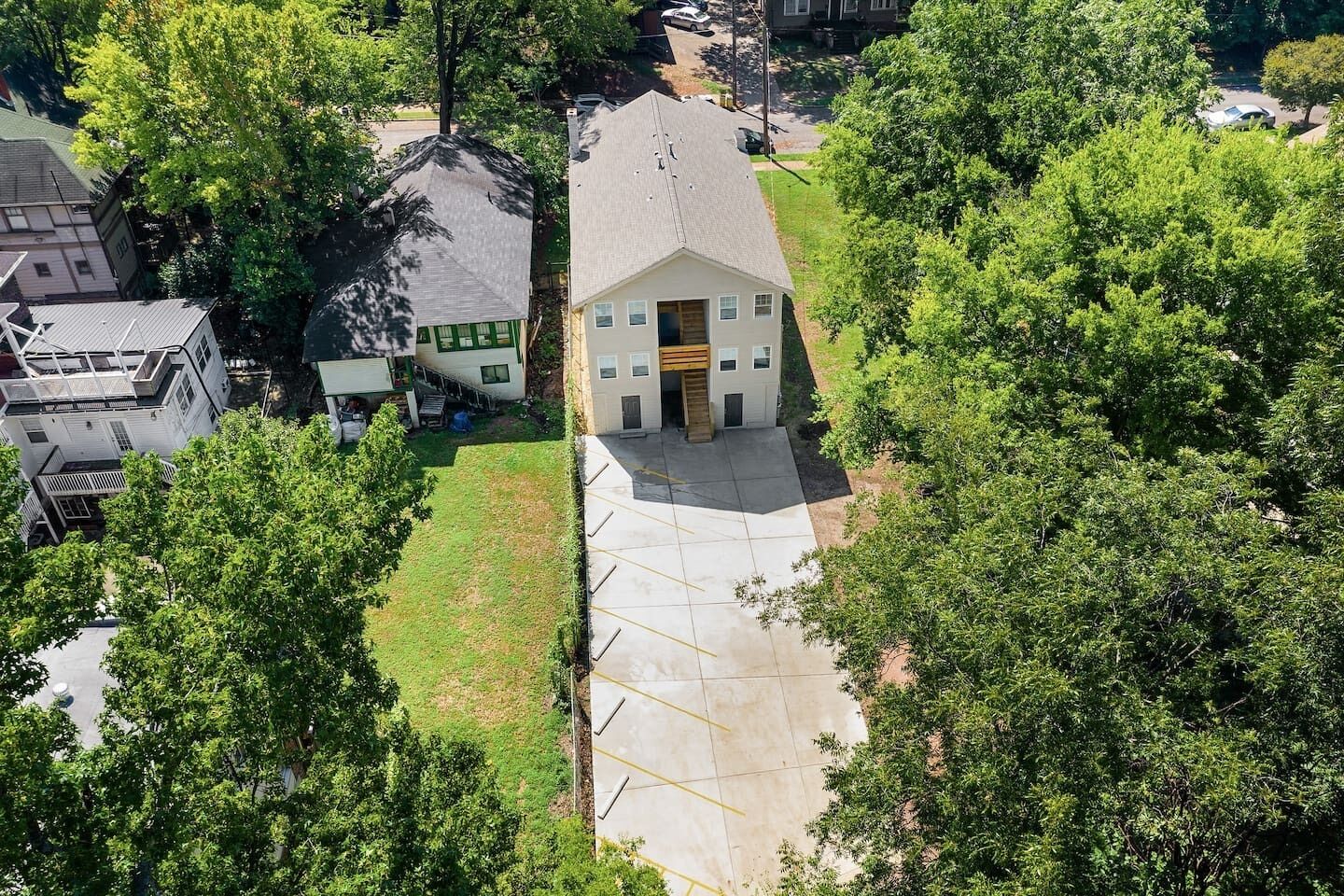 Vista aérea de una casa con jardín delantero, entrada para coches y árboles circundantes.