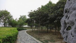 A paved pathway in a park with a rock wall and trees. - Henghui Binle Hotel (Shijiazhuang Zhonghua North Street Branch) (Shijiazhuang)
