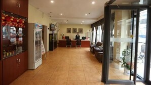 A hotel lobby with a reception desk, seating area, and a glass door leading outside. - Henghui Binle Hotel (Shijiazhuang Zhonghua North Street Branch) (Shijiazhuang)