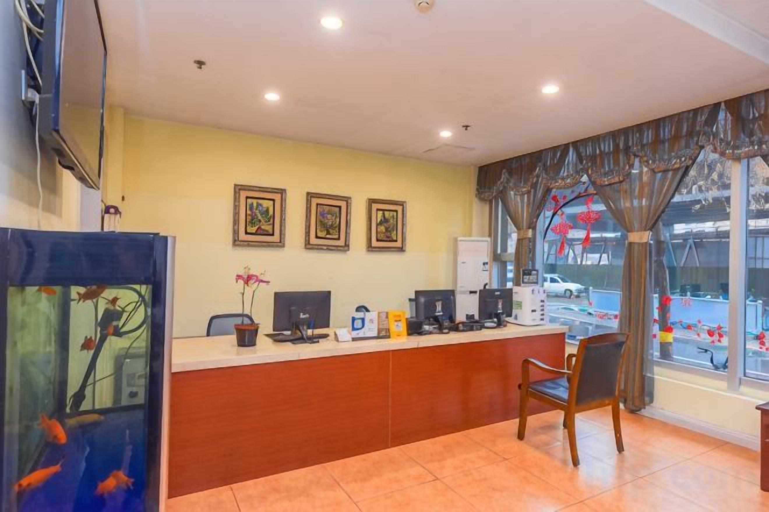 A reception desk with a computer, a telephone, and a small plant. There are three framed pictures on the wall above the desk.