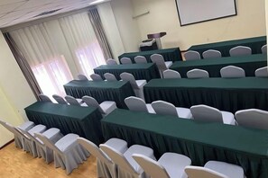 A conference room with multiple tables and chairs, a projector screen, and a window with curtains. - Henghui Binle Hotel (Shijiazhuang Zhonghua North Street Branch) (Shijiazhuang)