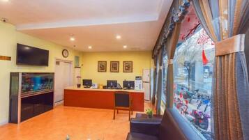 A hotel lobby with a reception desk, seating area, and a large window with a view of the street.