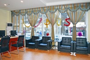 A reception area with a desk, chairs, and large windows with curtains. - Henghui Binle Hotel (Shijiazhuang Zhonghua North Street Branch) (Shijiazhuang)