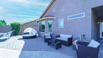 Sunny private patio with cushioned lounge seating and a cabana daybed