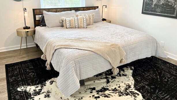 A neatly arranged bedroom with a large bed, two bedside tables, a window with blinds, and a world map on the wall.