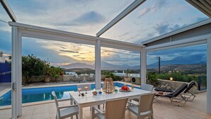 Zona de piscina con mesa y sillas, piscina y vistas del paisaje.
