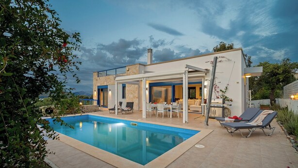 Una casa moderna con piscina, mobiliario de exterior y un porche cubierto.