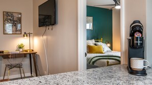 Una cocina moderna con encimera de granito, cafetera y comedor con una silla y una mesa.