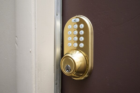 A gold door lock with a numeric keypad.