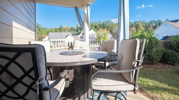 Eine überdachte Terrasse mit einem runden Tisch und vier Stühlen, mit Blick auf eine Wohngegend.
