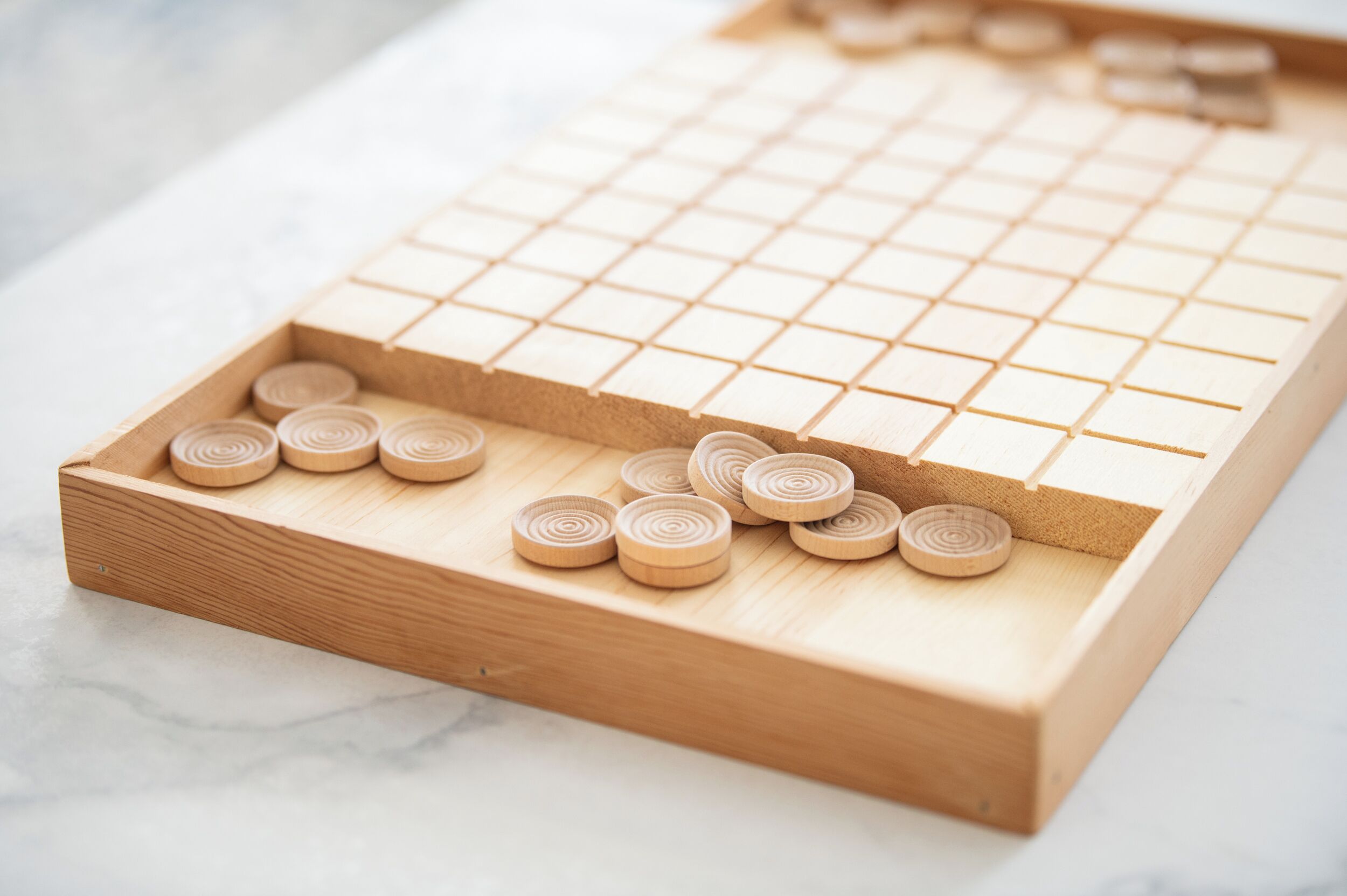 A wooden board game with a grid and circular pieces.