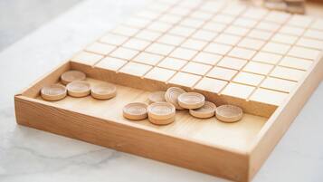 A wooden board game with a grid and circular pieces.