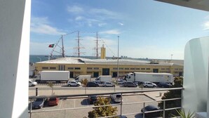 A view of a port with a large building, parked vehicles, and a flag.