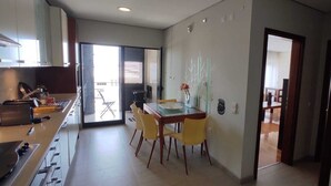 A modern kitchen with a dining area, a sliding glass door leading to an outdoor space, and a visible staircase.