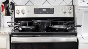 A kitchen with a stove, pots, and a digital clock displaying 10:33.