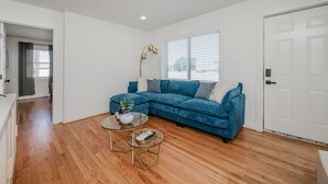 A living room with a blue sectional sofa, a glass coffee table with decorative items, and a tall floor lamp.