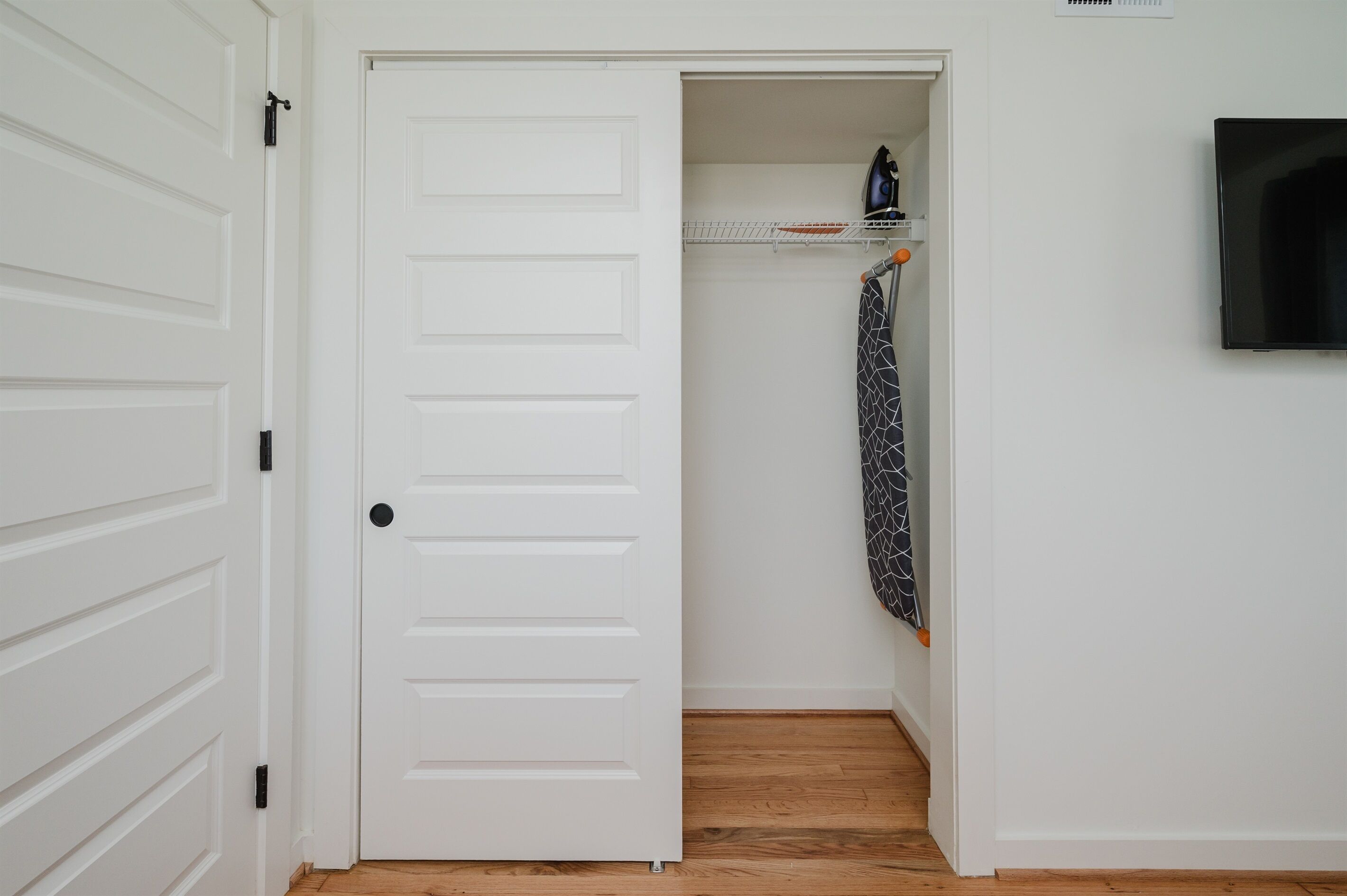 A white door leading to a closet with a hanging garment.