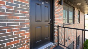 A brick building with a black door and a small porch area.