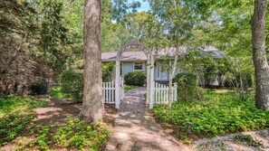 A garden pathway leading to a gazebo with a white picket fence.